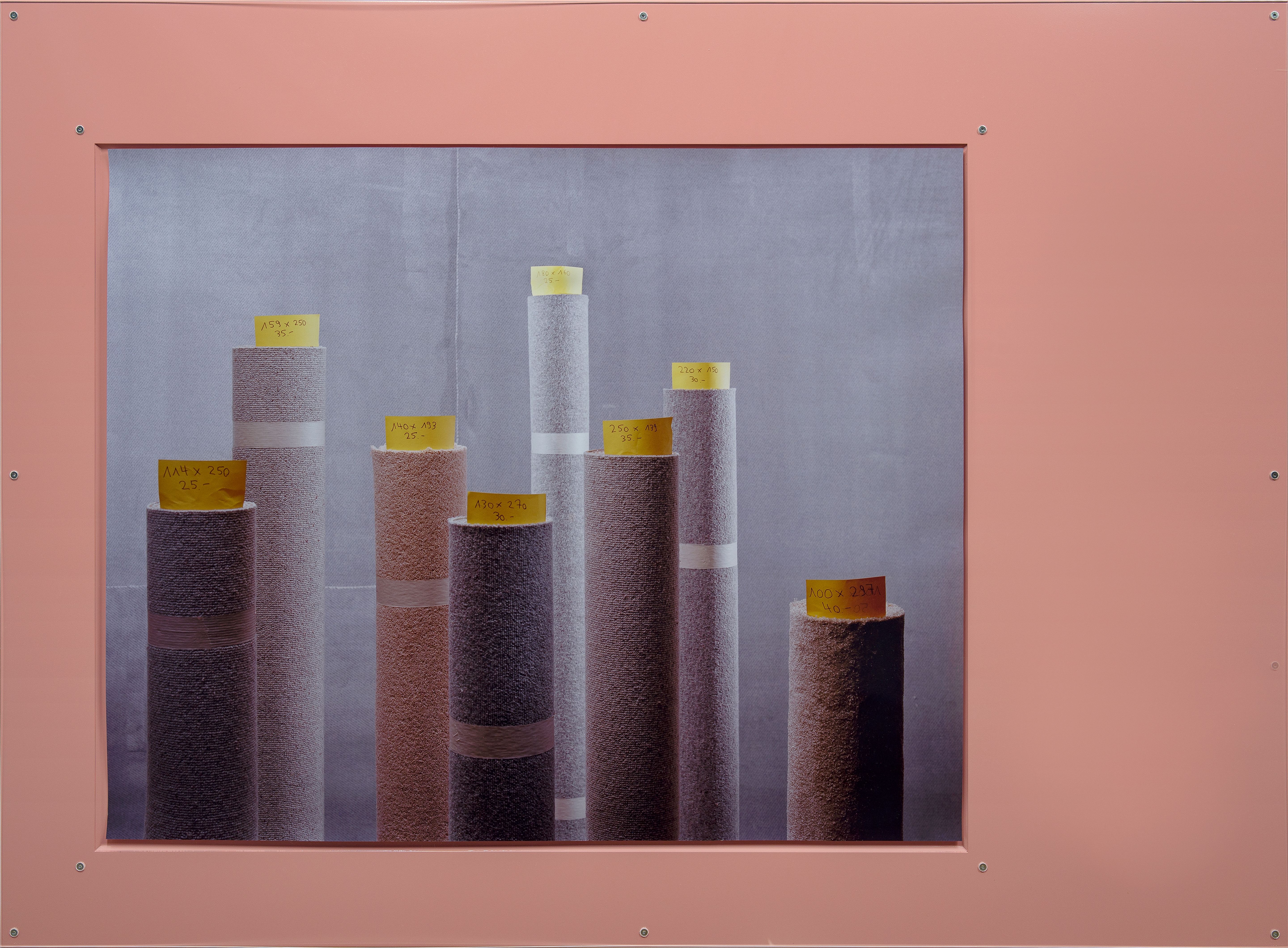Différents rouleaux de tissu avec des étiquettes dans un cadre rose.