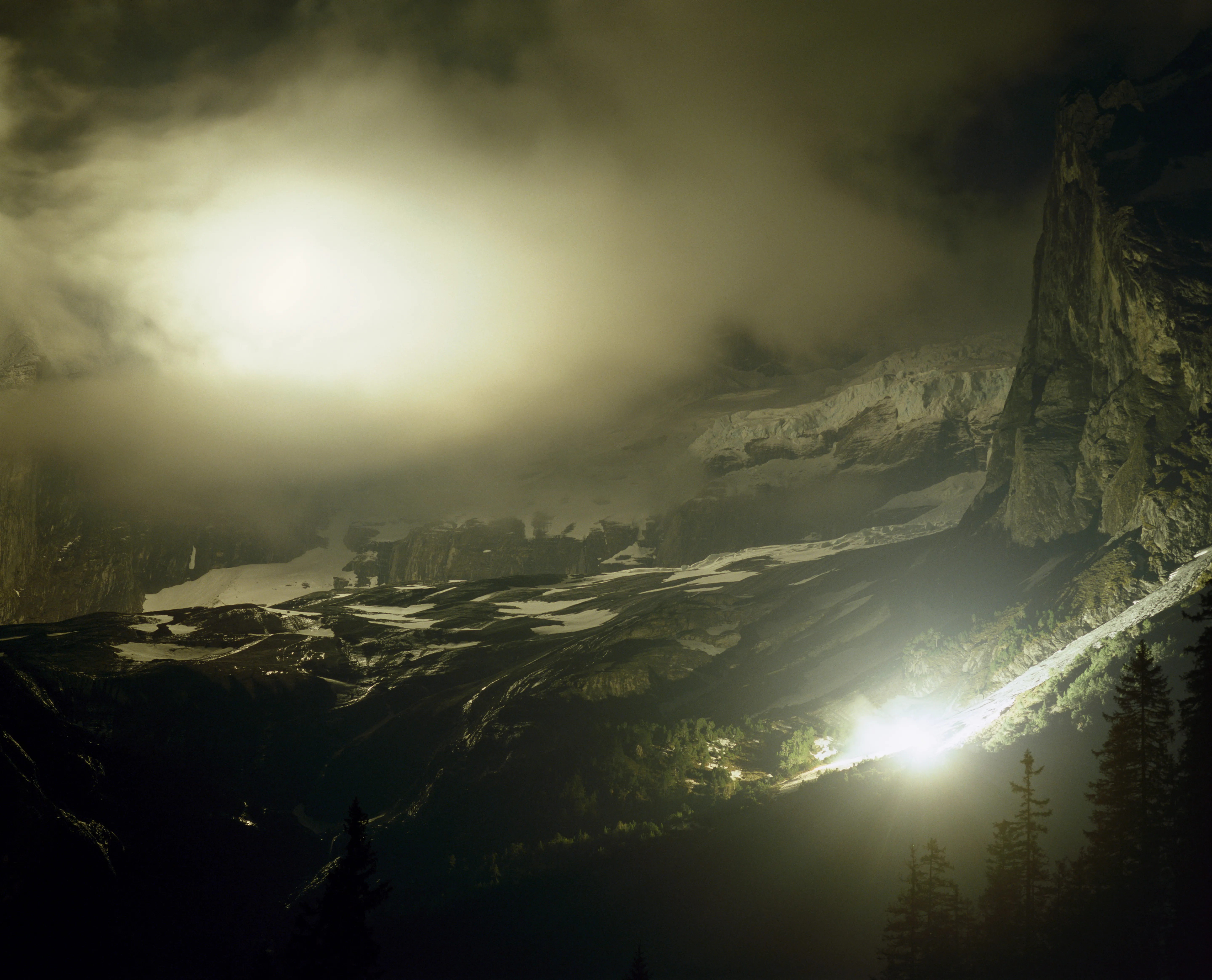 Sommet de montagne brumeux la nuit avec deux lumières vives.
