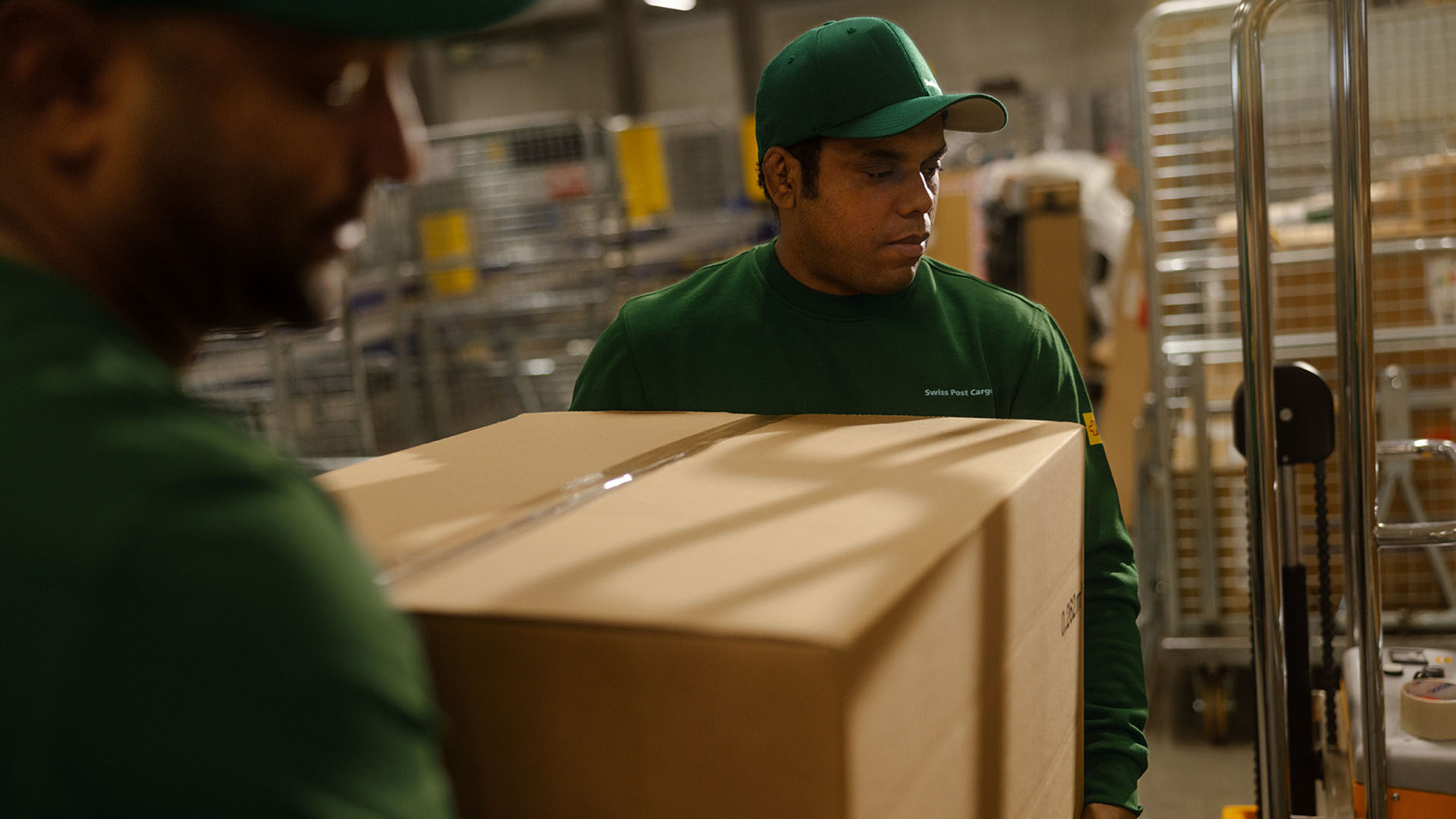 Due dipendenti di Swiss Post Cargo consegnano merci durante la notte in un negozio.