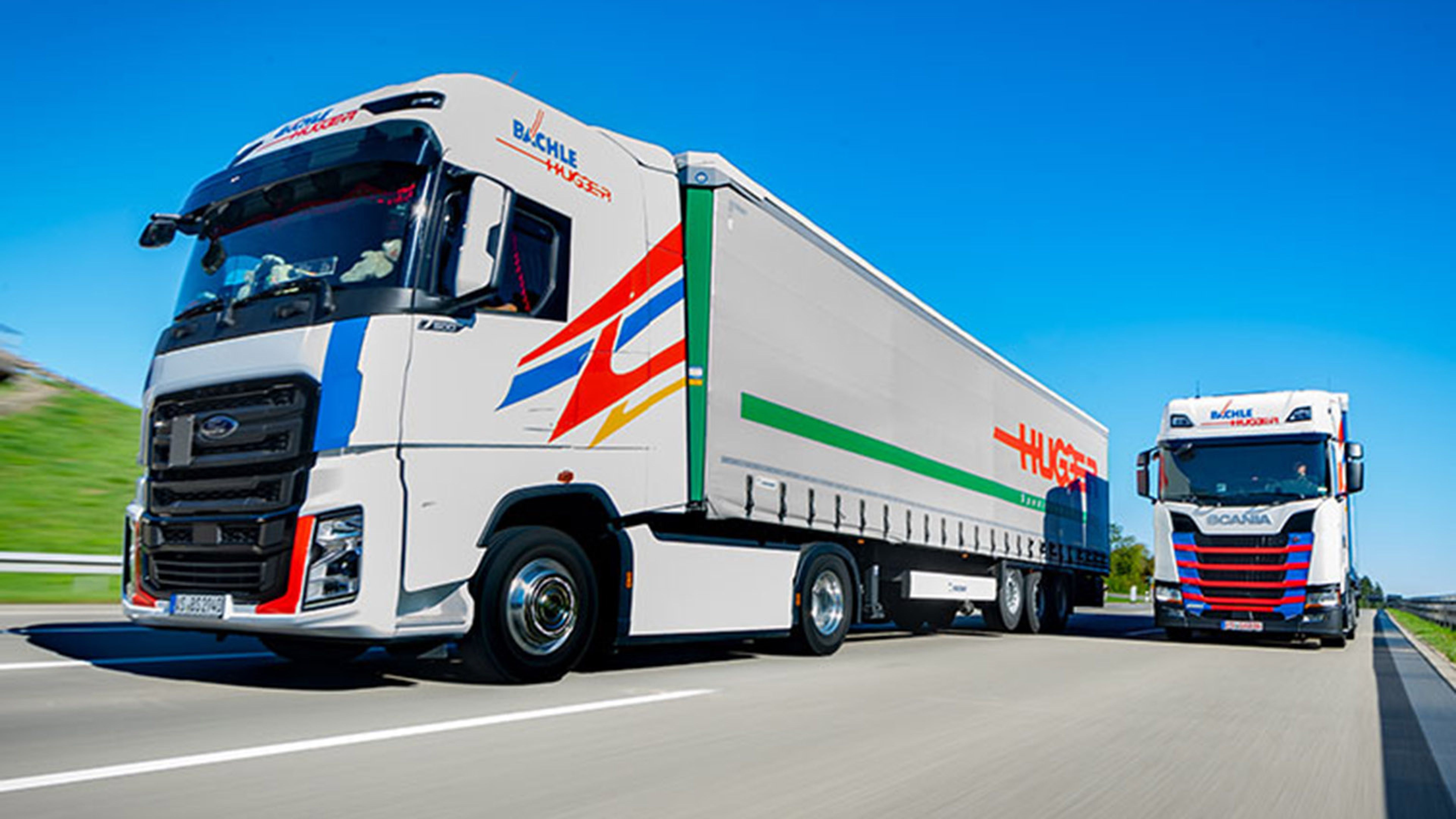 A Swiss Post Cargo truck and a Bächle truck are parked side by side.