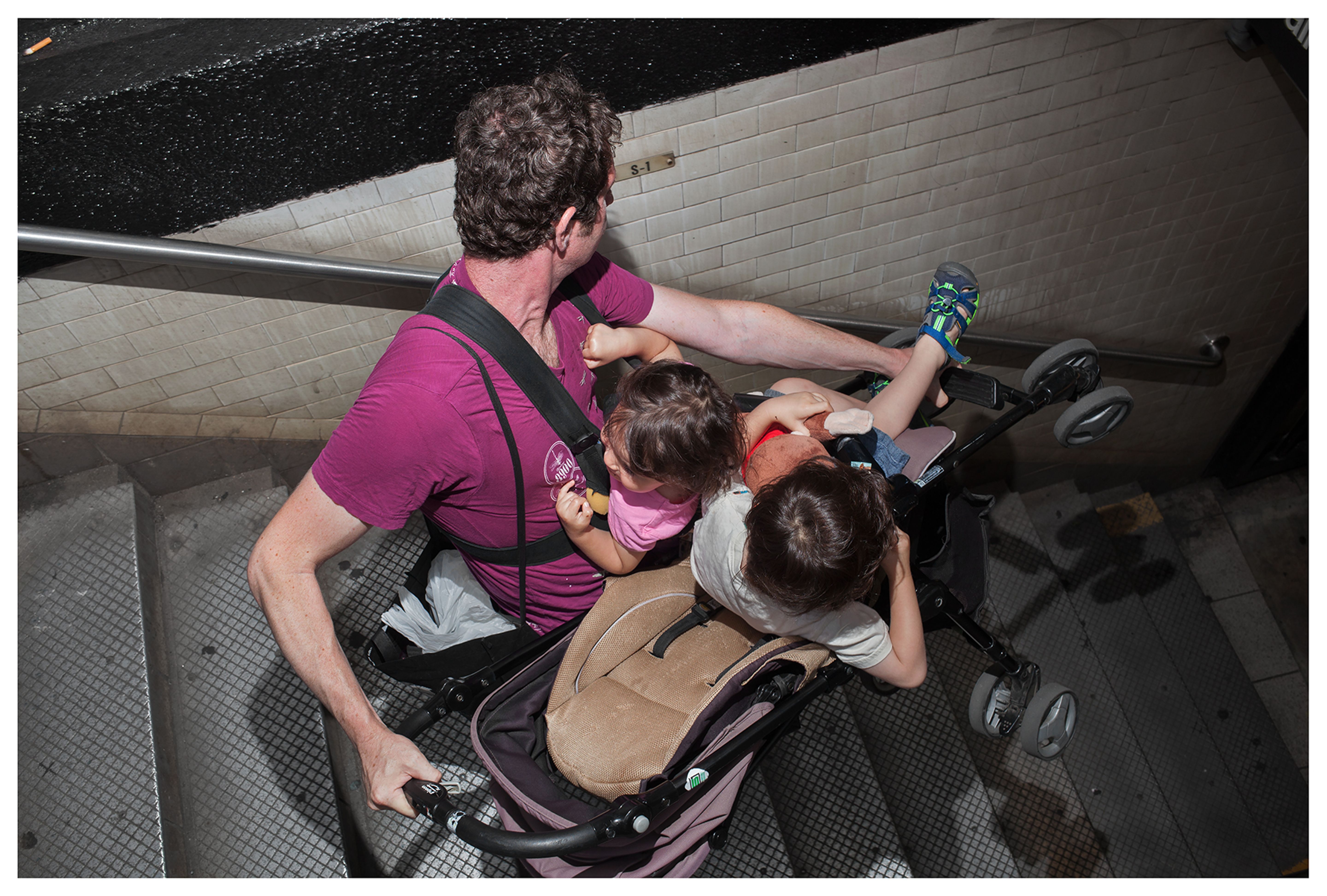 Un homme monte un escalier avec un enfant et une poussette.