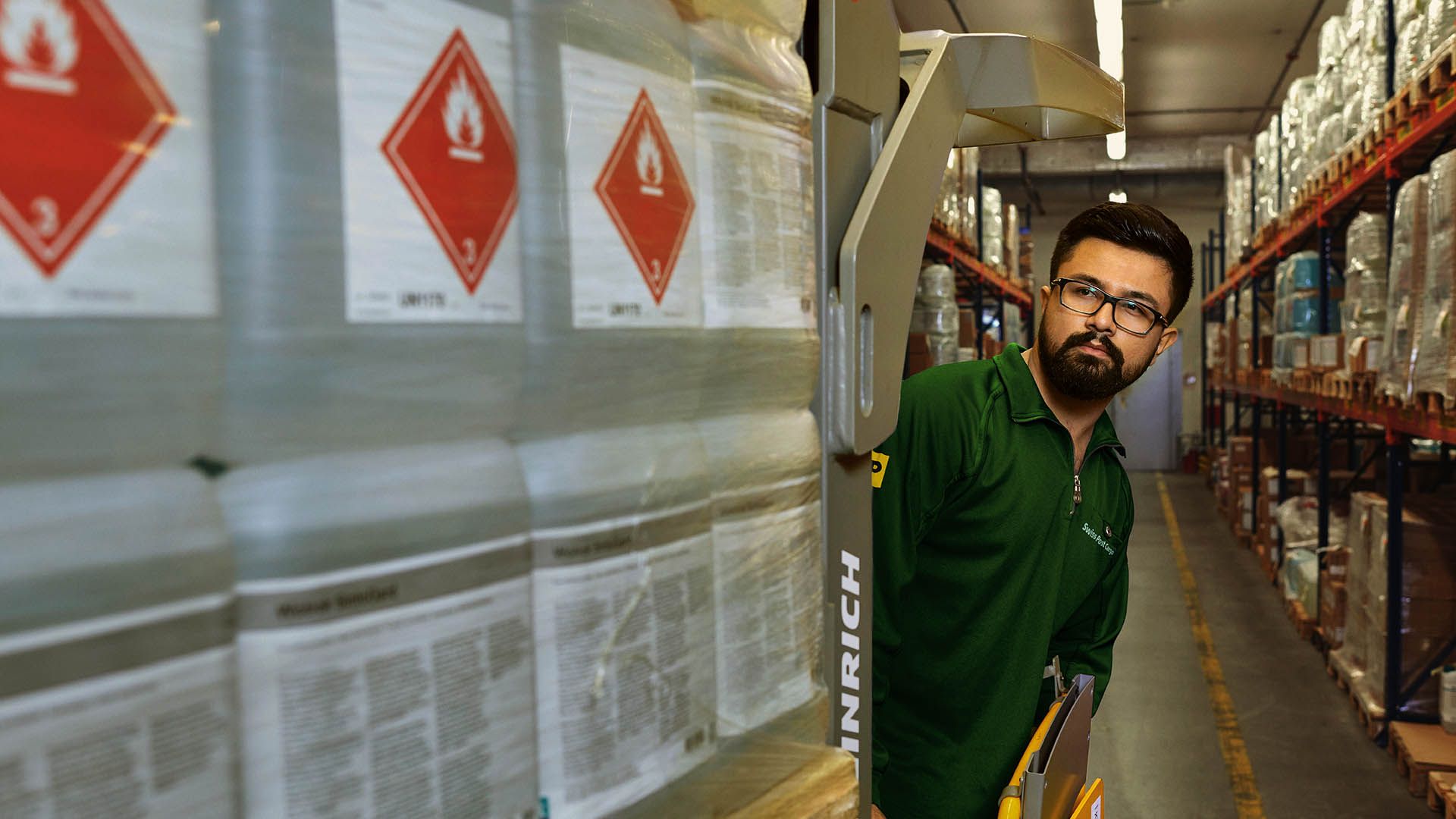 Un magasinier transporte des marchandises dangereuses sur un transpalette dans l’entrepôt de stockage des matières dangereuses.