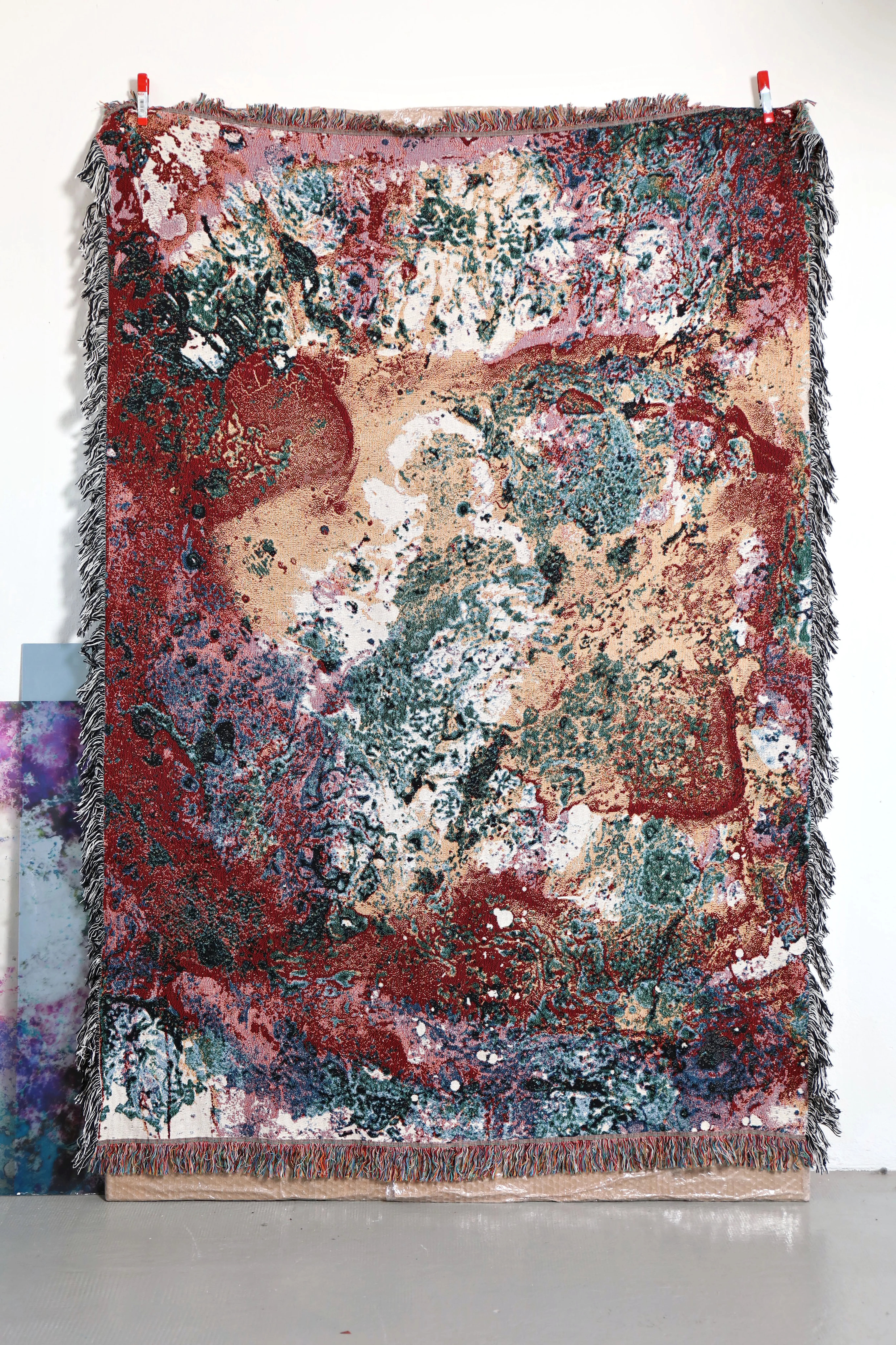 Un tapis multicolore à motifs est accroché à un mur blanc.