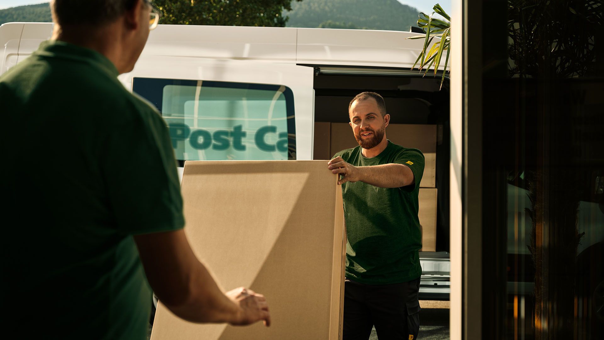 Due dipendenti di Swiss Post Cargo scaricano una consegna ingombrante da un veicolo.