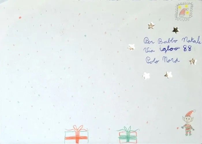 Carte de Noël dessinée à la main avec beaucoup d’espace blanc, des petits cadeaux en bas et un personnage avec bonnet rouge en bas à droite. En haut à droite, l’adresse « Per Babbo Natale, via Igloo 88, Polo Nord », décorée avec des étoiles dorées et un timbre.