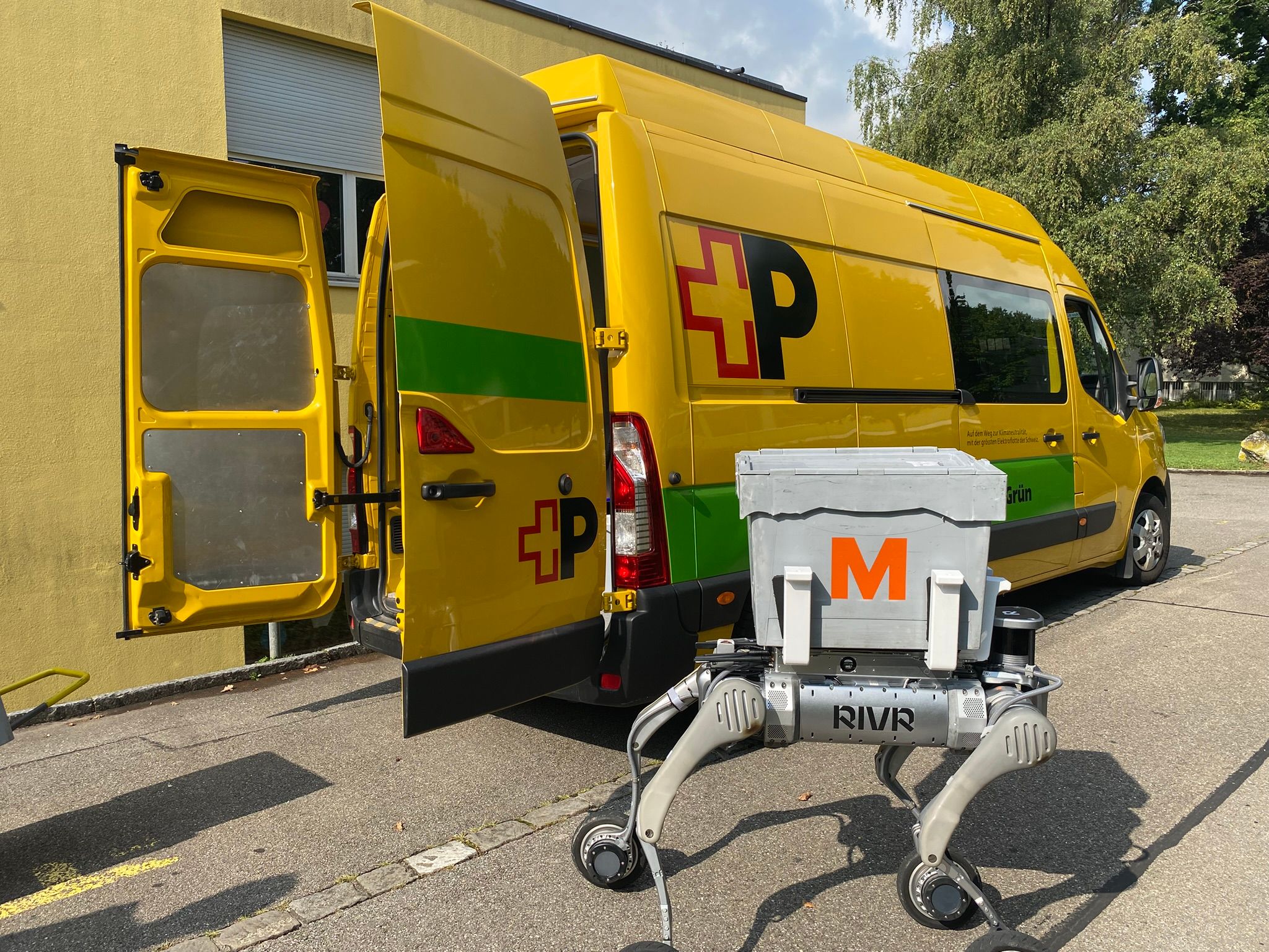 Gelber Post-Transporter mit geöffneten Hecktüren, davor ein vierbeiniger Roboter mit grauer Transportbox, markiert mit rotem M.