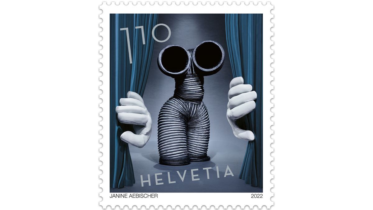Briefmarke mit der Aufschrift ‚Helvetia 110‘. Darstellung einer Figur aus grauen, flexiblen Schläuchen mit zwei großen runden Öffnungen als Augen. Die Figur hält blaue Vorhänge zur Seite. Unten steht ‚Janine Aebischer‘ und das Jahr 2022.
