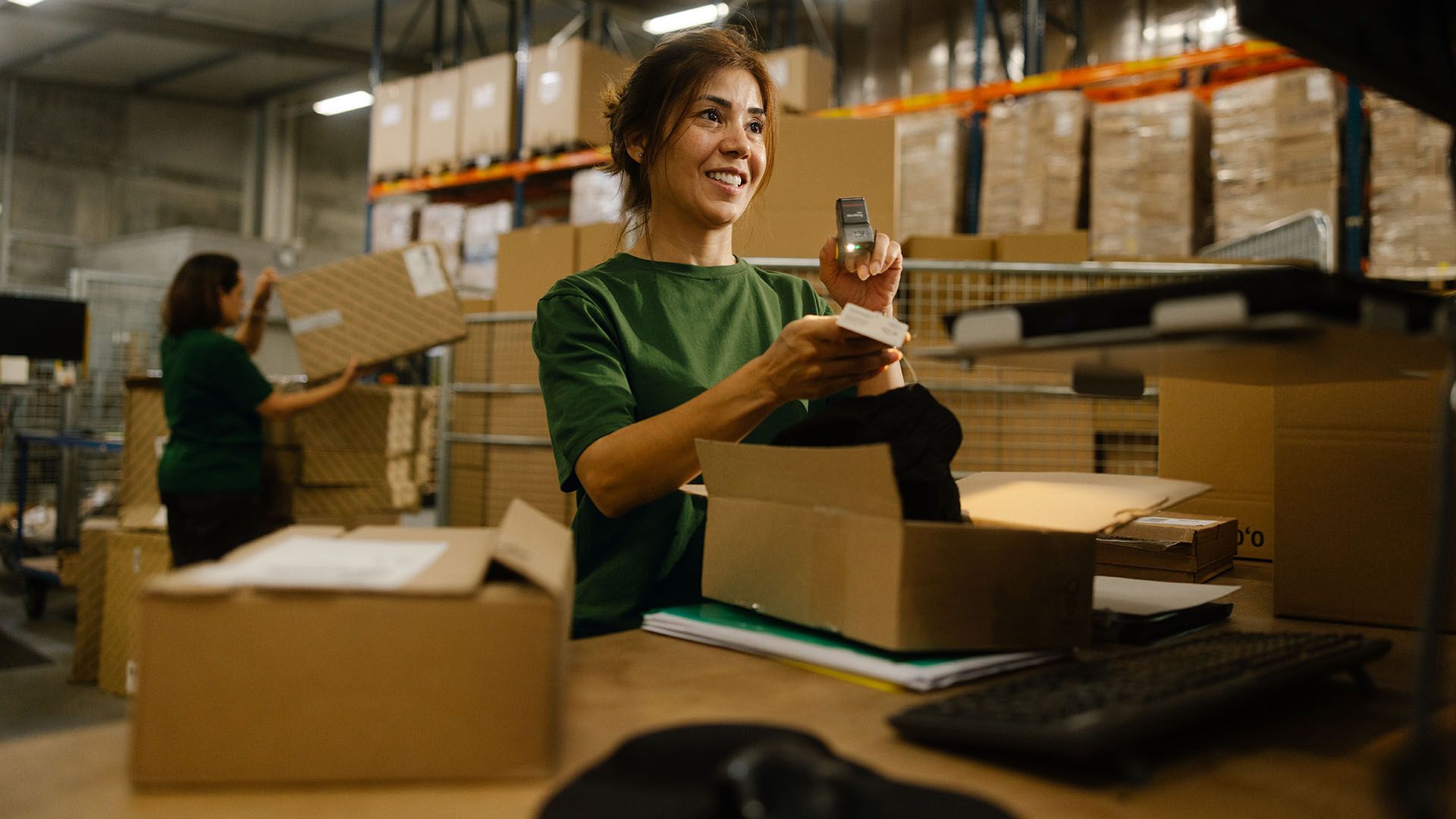 A Swiss Post Cargo employee checks the contents of a returned package. In the background, another employee loads a package onto a trolley.