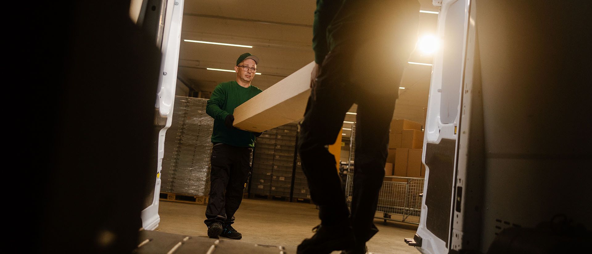 A night courier from Swiss Post Cargo delivers medical goods with a hand truck, with a delivery vehicle in the background.