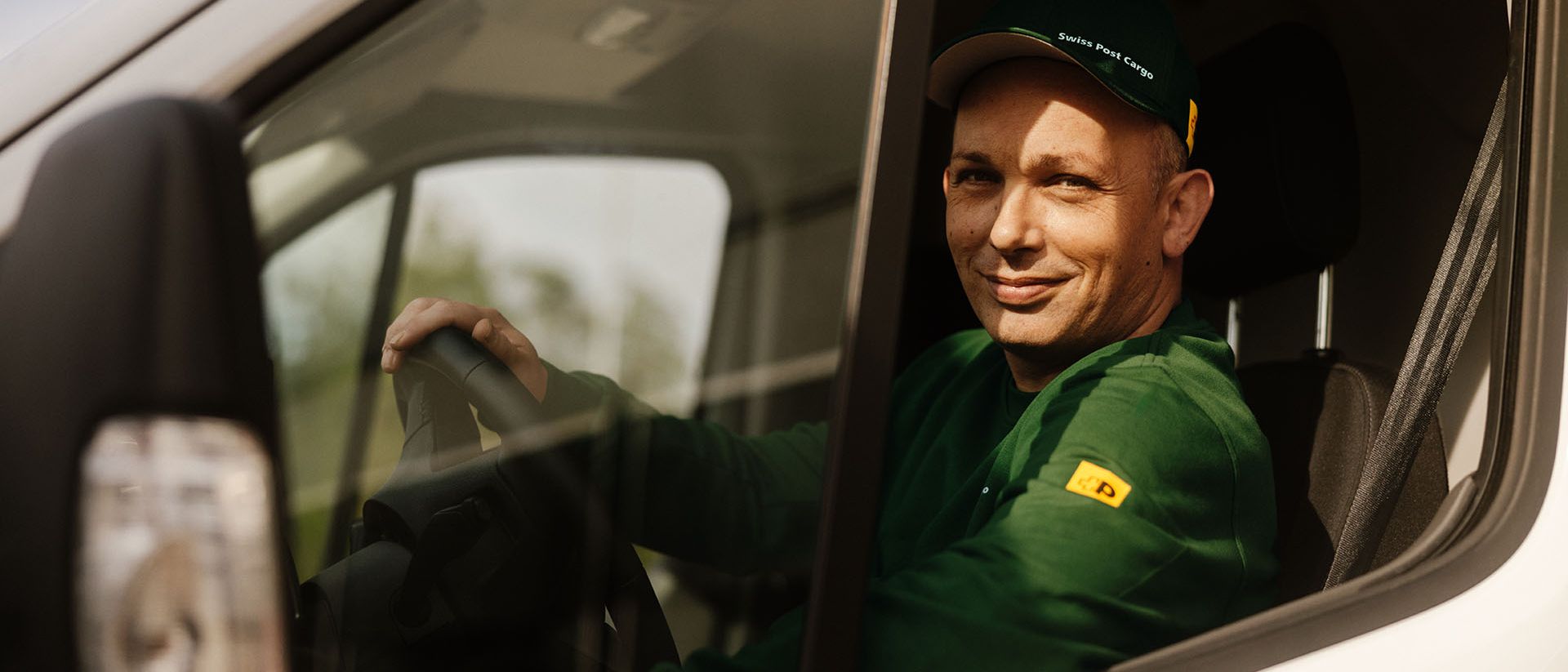 A Swiss Post Cargo driver operates a delivery vehicle for daytime shipments.