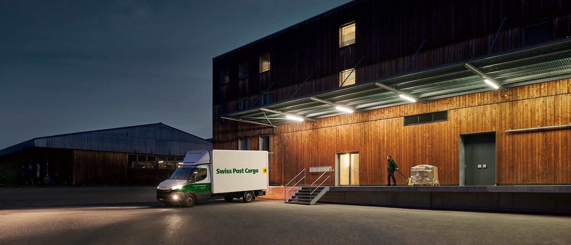 A night courier from Swiss Post Cargo delivers goods to a warehouse before dawn.