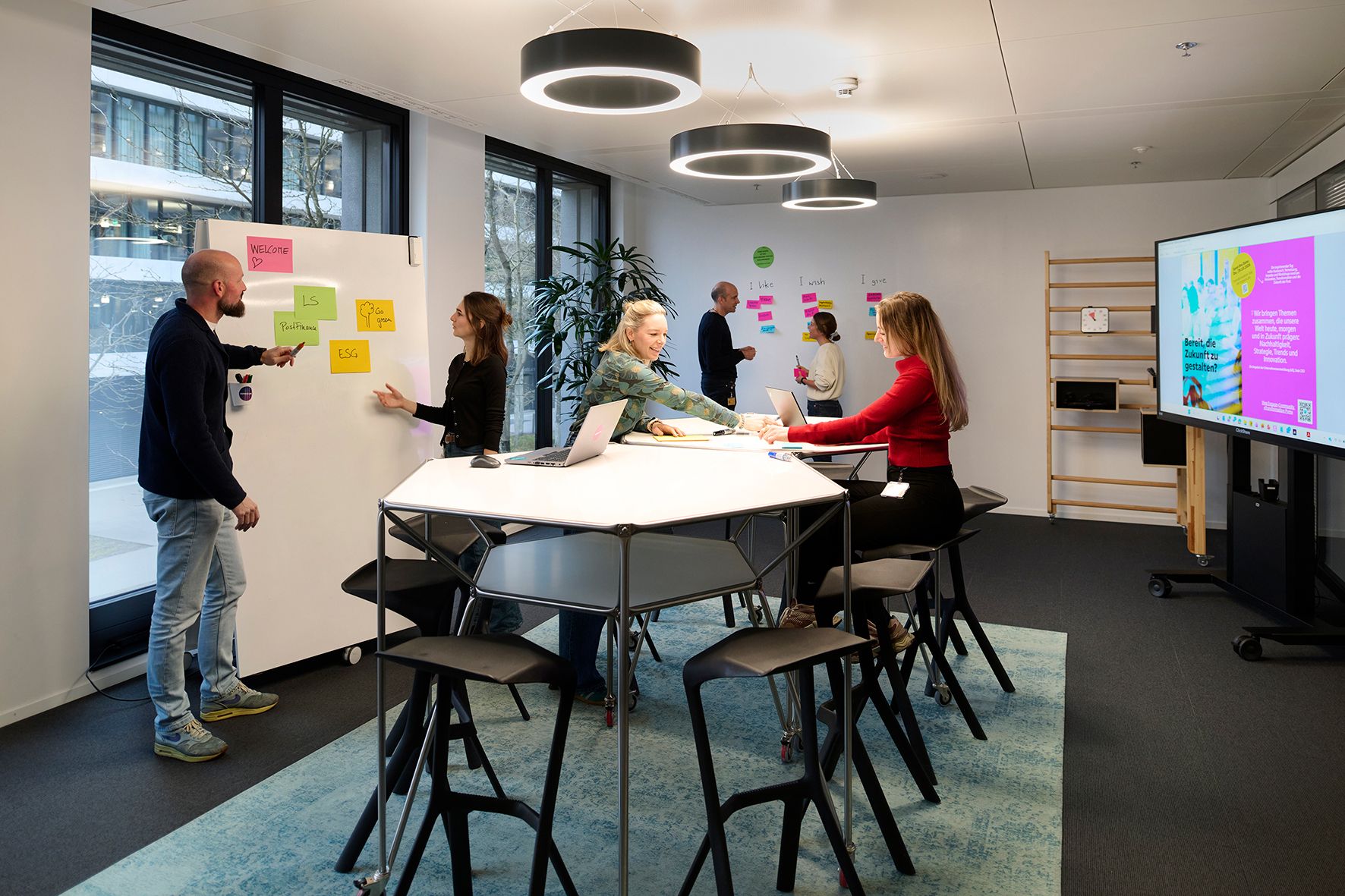 A group of people working in a modern office with boards and laptops.