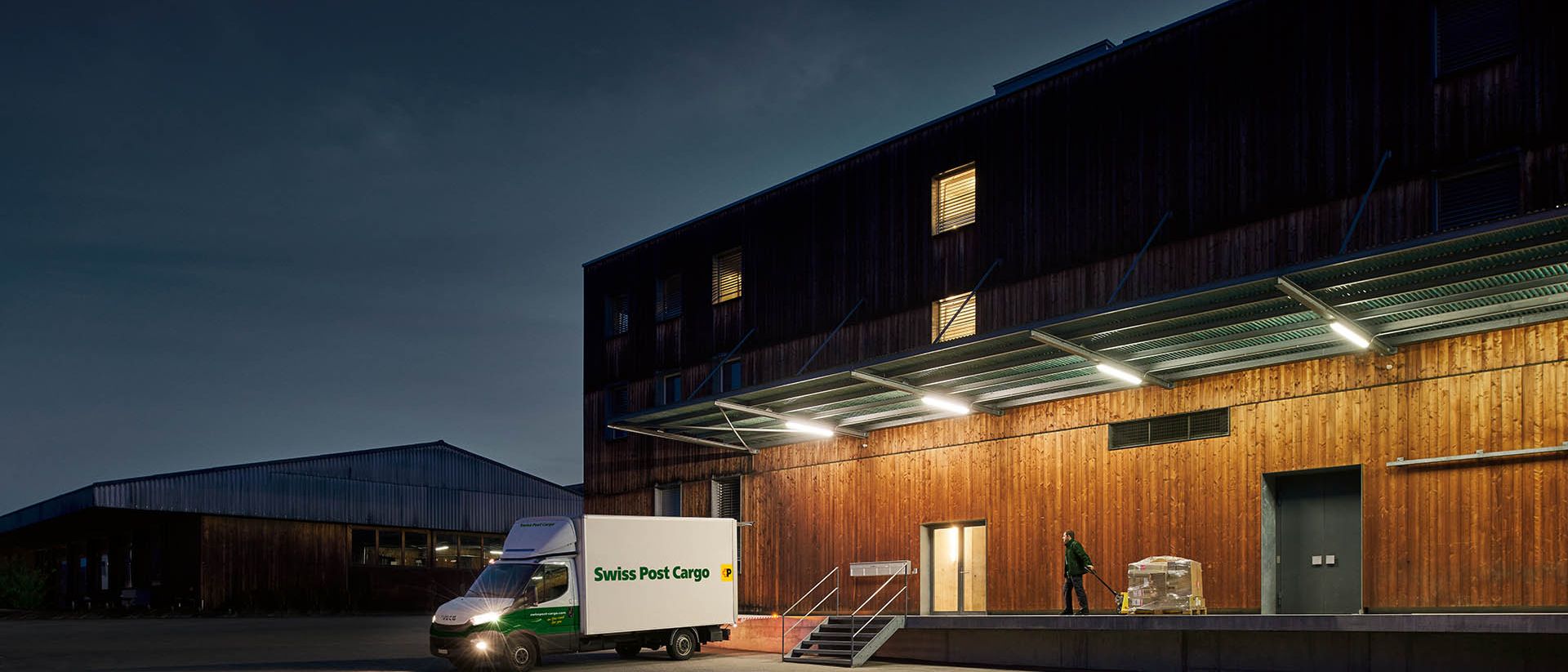 Un coursier de nuit de Swiss Post Cargo livre des marchandises à un bâtiment d'entrepôt avant l'aube.