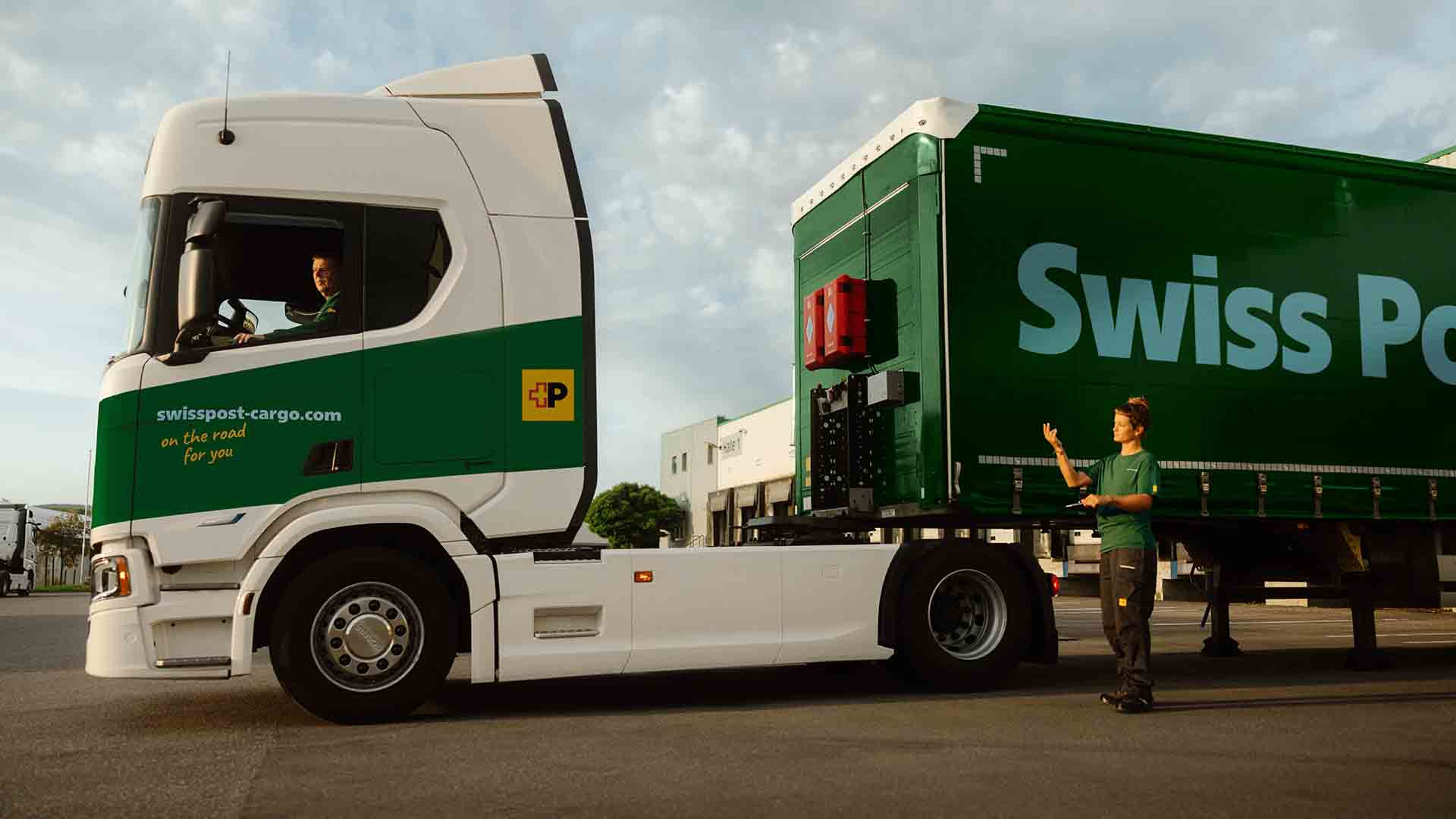 Un chauffeur de camion Swiss Post Cargo attelle une remorque, assisté par une collègue.
