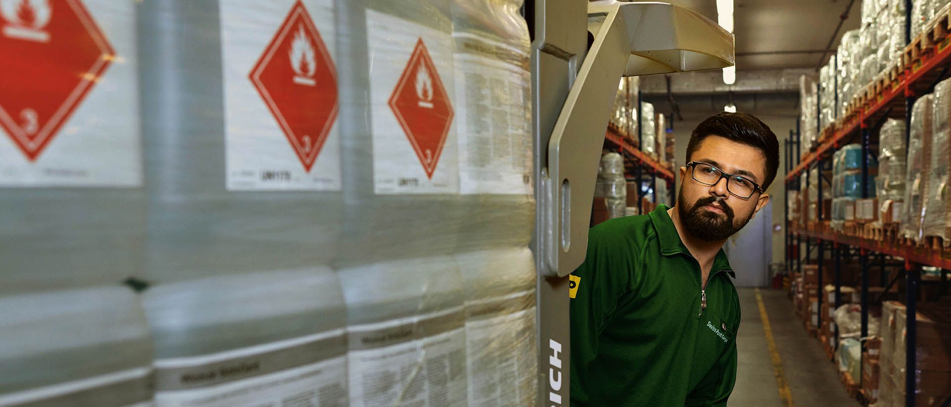 Un magasinier transporte des marchandises dangereuses sur un transpalette dans l’entrepôt de stockage des matières dangereuses.