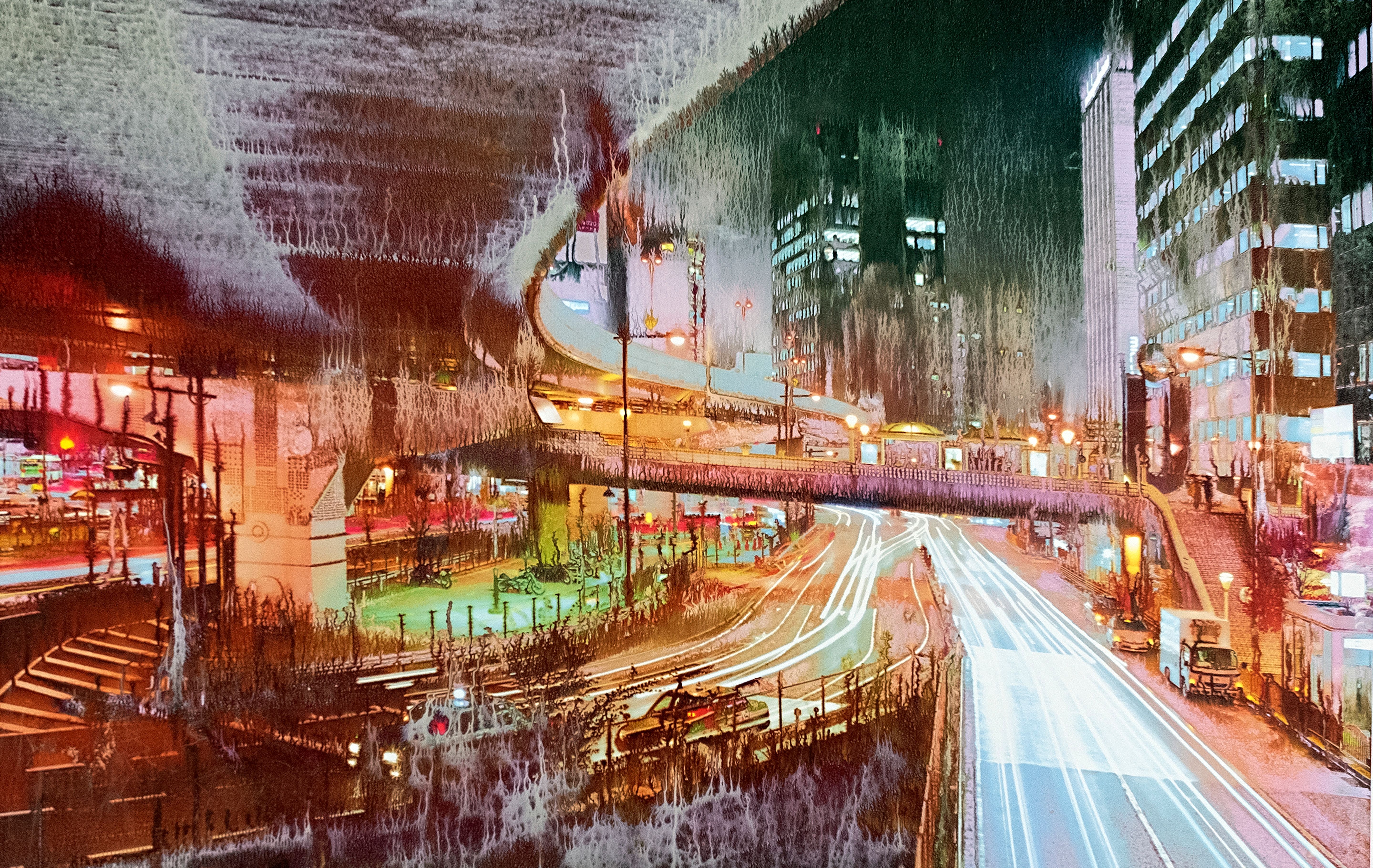 Foto notturna di una città con tracce luminose di veicoli e architettura urbana.