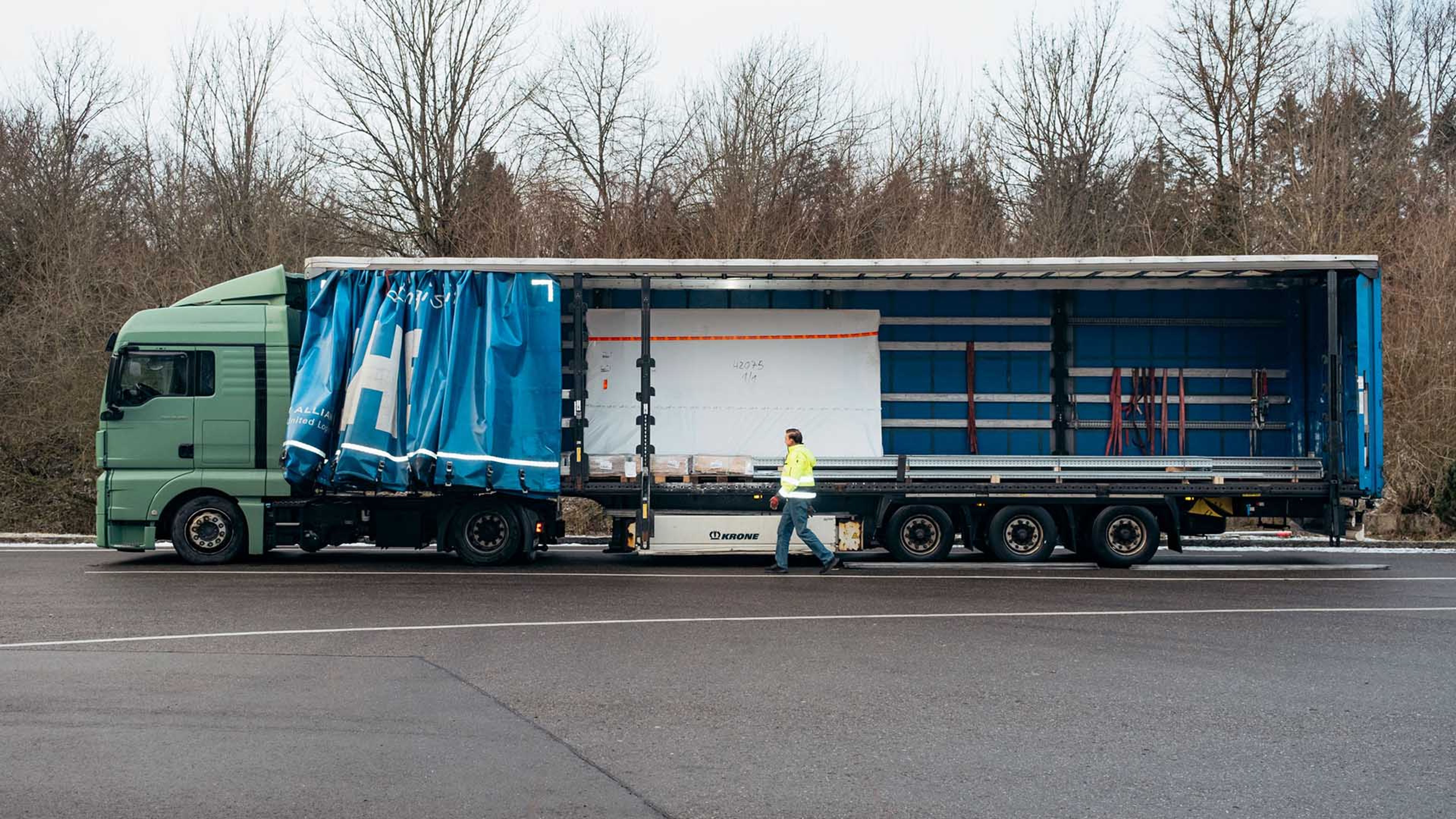 Francisc Szobo steht seitlich vor LKW-Anhänger mit geöffneter Plache.